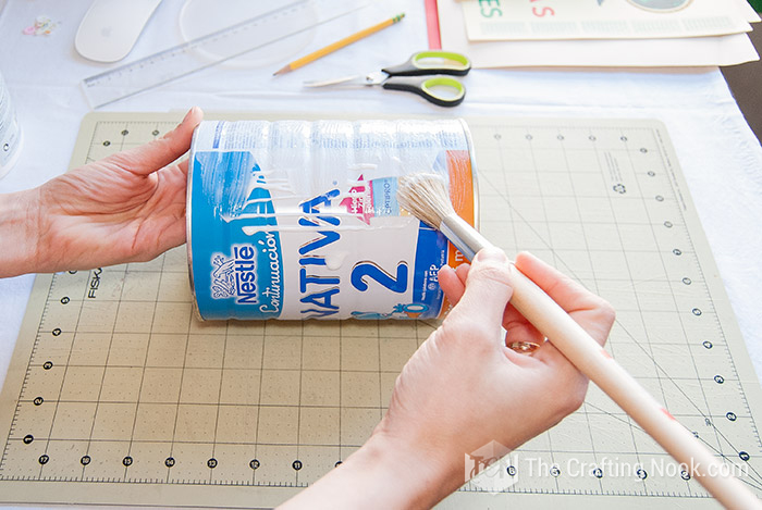 Applying  white glue with the brush to the tin can