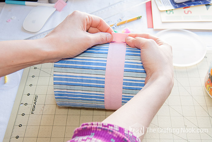 placing a pink ribbon around the can
