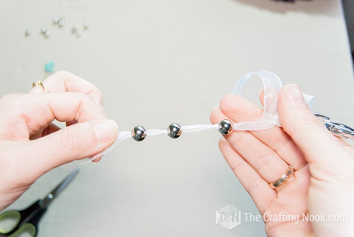 showing three beads on one of the ribbon and with their respective knots.