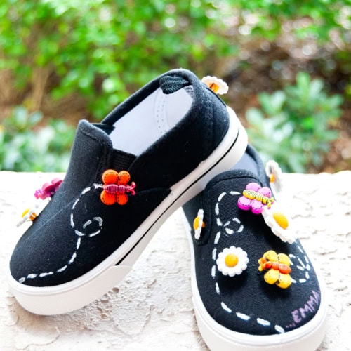 DIY Embellished Shoes with Daisy and Butterfly Buttons laying on a flat surface one slightly on top of the other. Feature image