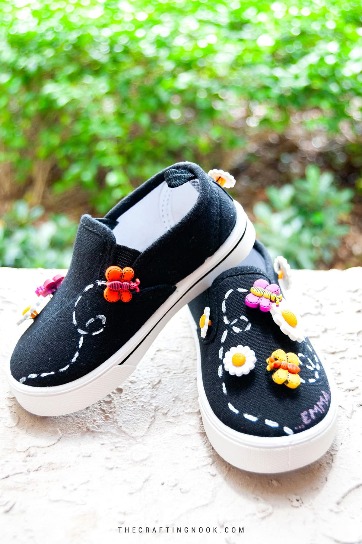 DIY Embellished Shoes with Daisy and Butterfly Buttons laying on a flat surface one slightly on top of the other. Feature image