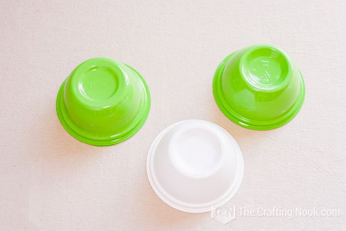 view of three small painted plastic containers, two green and one white
