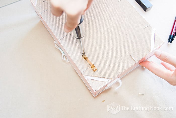 rear view of fruit crate hand screwing a wall hanger
