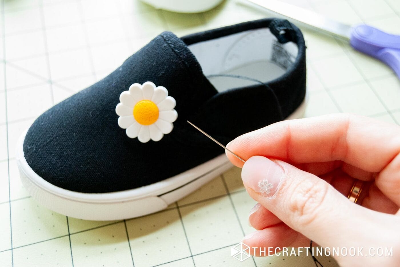 placing the daisy button on one side of the shoe and sewing it by hand
