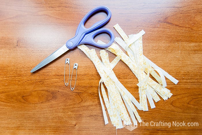 view of scissor,  safety pins and fabric strip