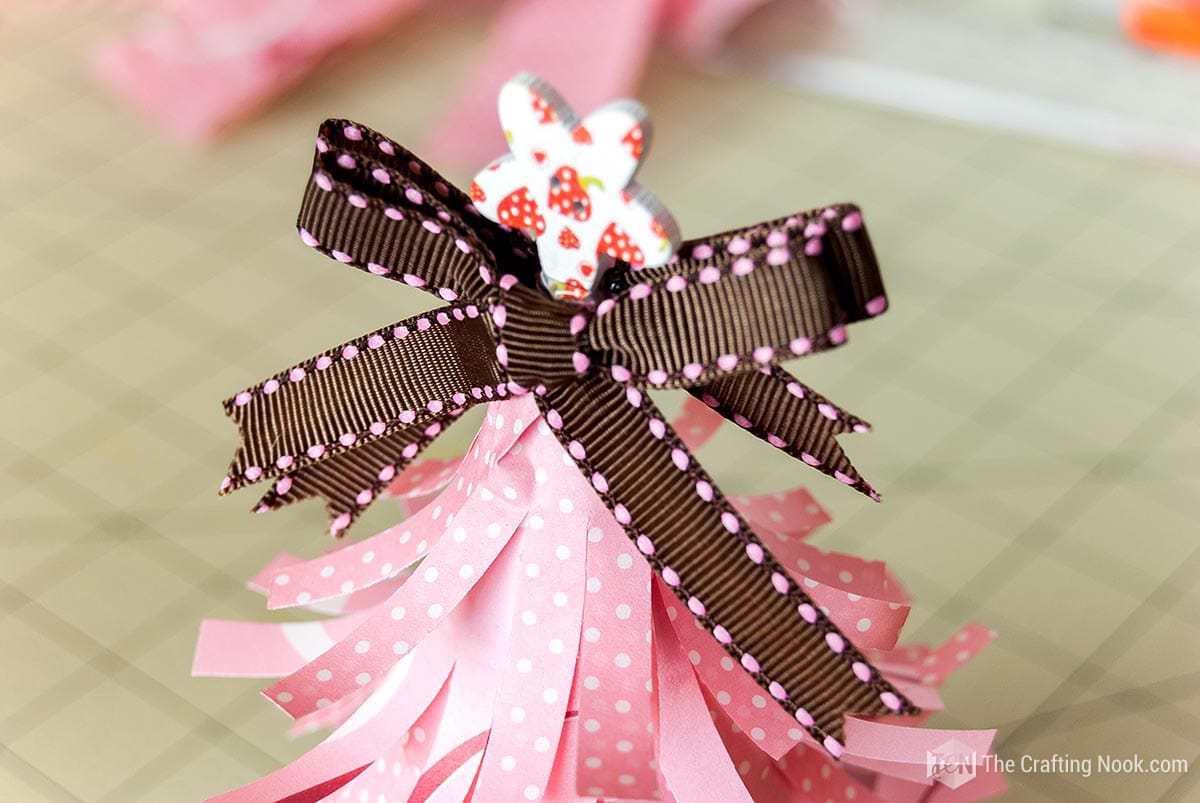 close view of the tip of the tree with a bow and a decorative button
