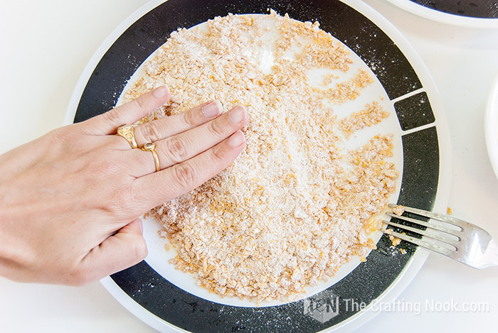 top view of hand pressing tender chicken into batter mixture