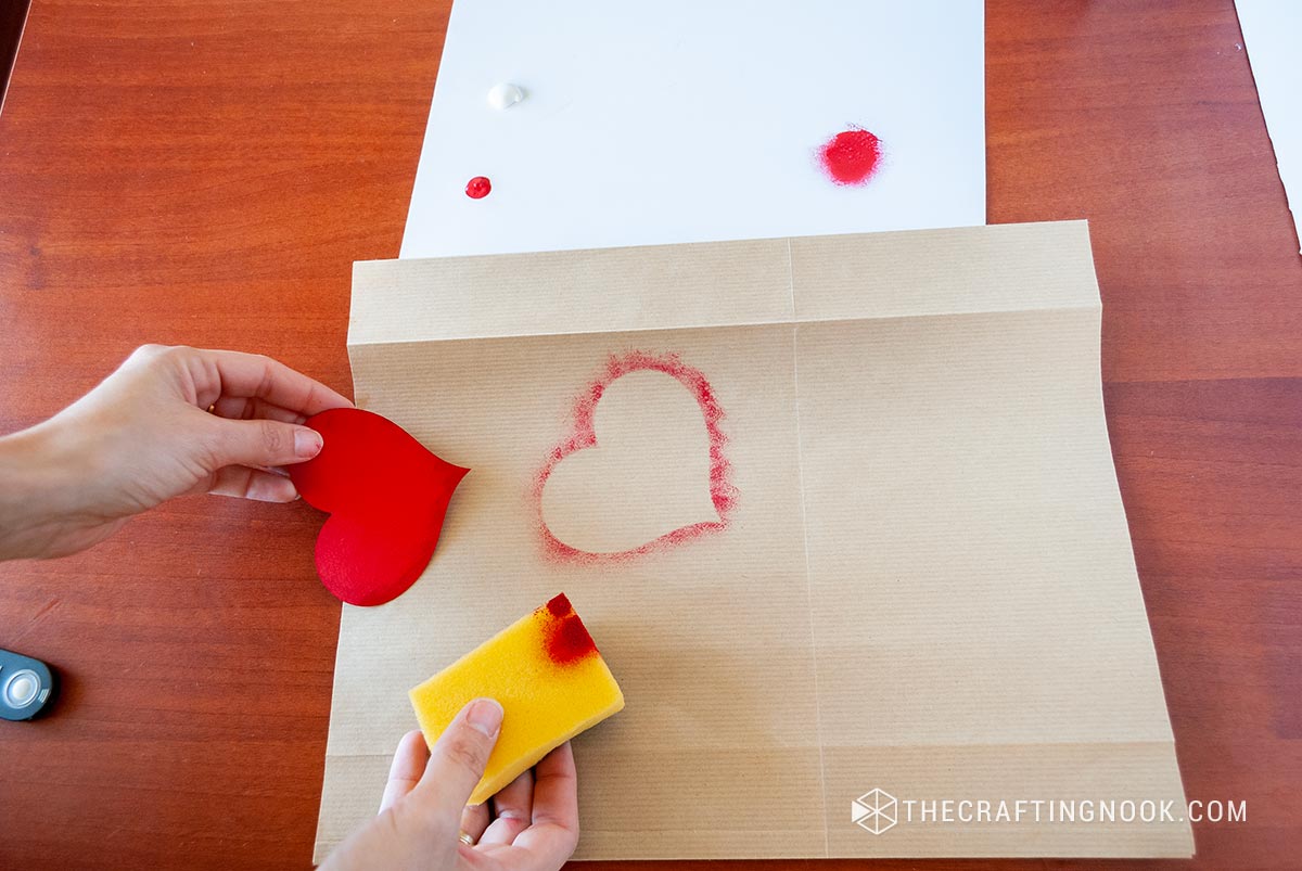 showing how the result of the sponge painting technique looks on the paper bag using a heart stencil
