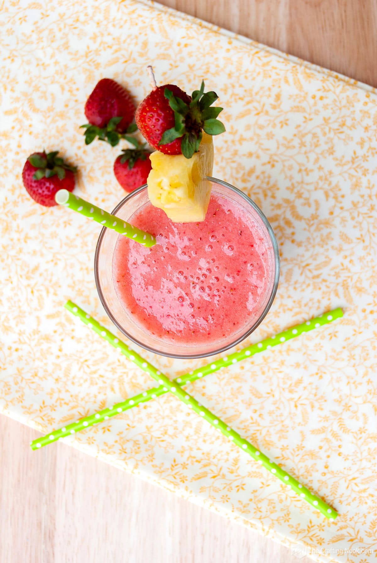 Overhead view Strawberry Banana Pineapple Smoothie Recipe, decorated with pineapple wedges and strawberry on a table