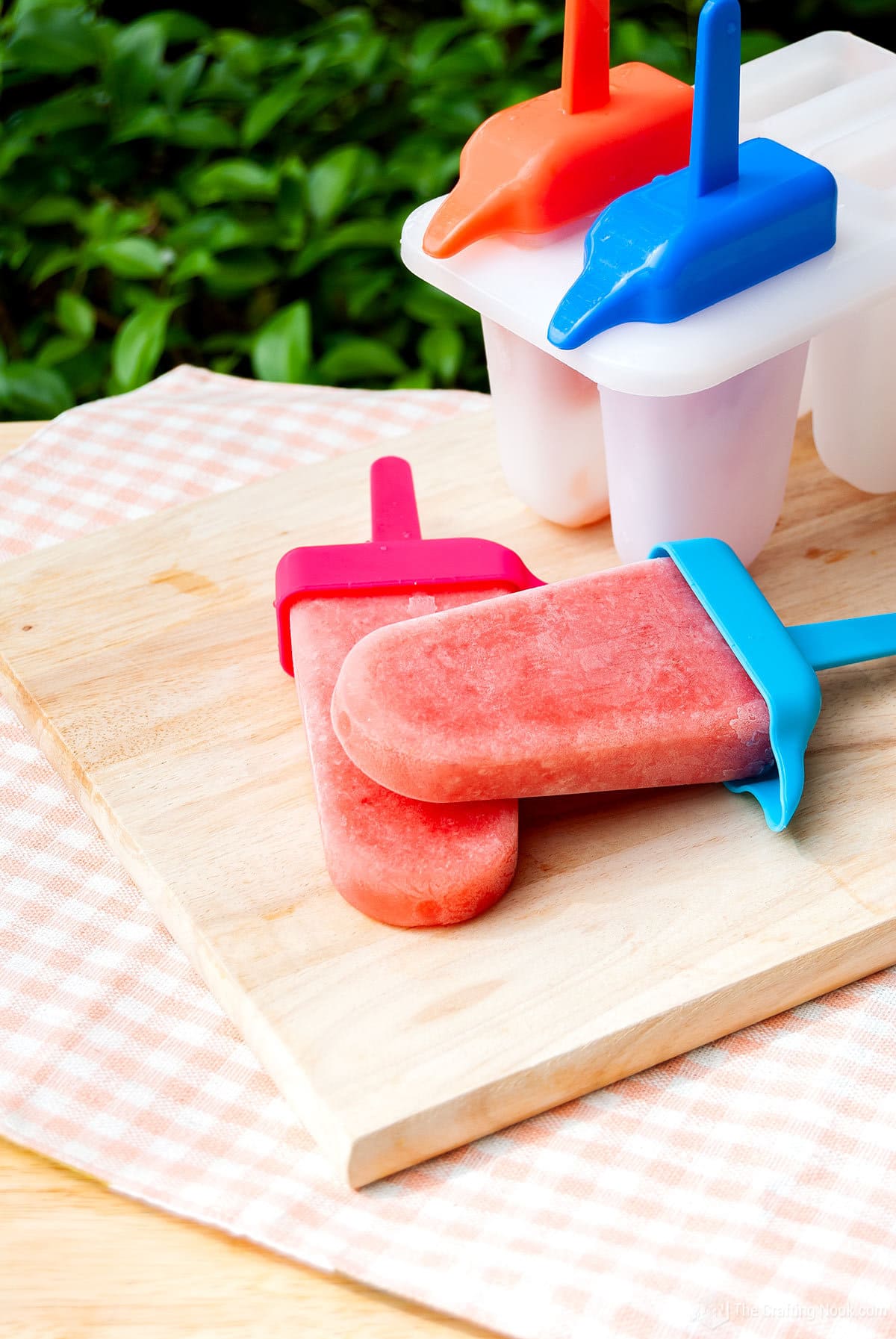 45 degree angle shot of the Easy Fruit Smoothie Popsicles on a wooden board on a table