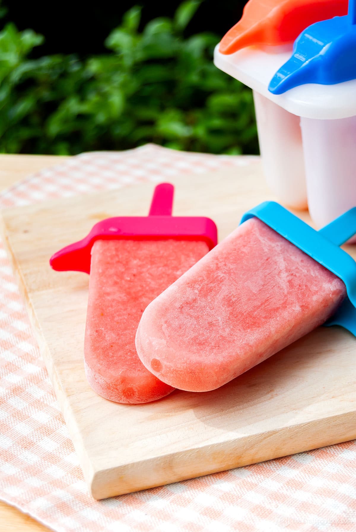 Closeup of 2 Easy Fruit Smoothie Popsicles on a wooden board on a table