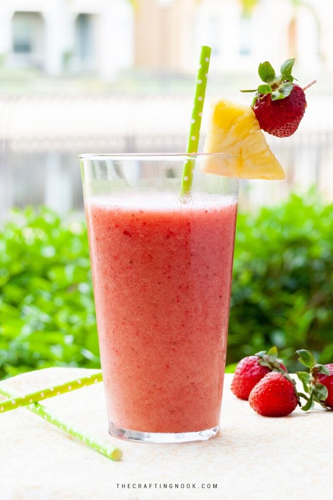 Strawberry Banana Pineapple Smoothie Recipe cover image, decorated with pineapple wedges and starwberry on a table