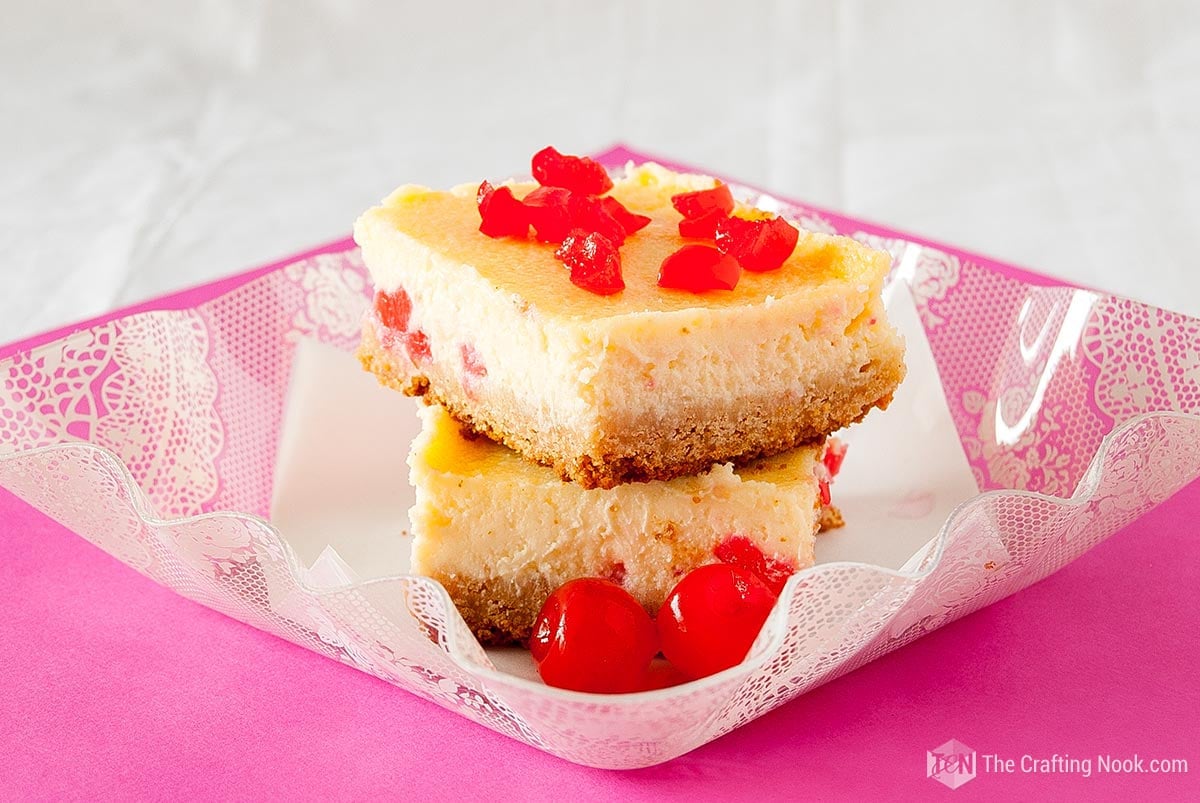 stack of two White Chocolate Cherry Cheesecake Bars  on a clear dish