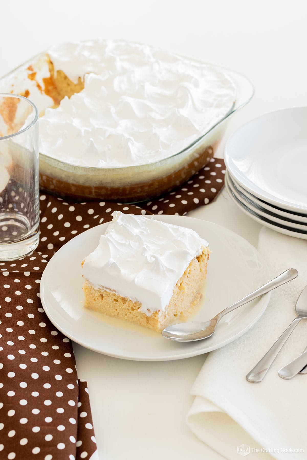 about 45 degree view of a piece of Tres Leches Cake (Three Milks Cake) in a white dish in front of the whole cake