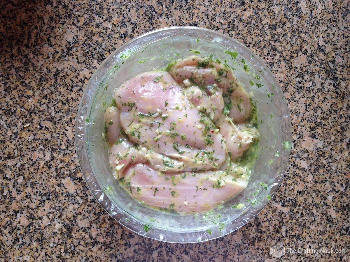 view from above of  bowl with the chicken breasts with the mixture covered with plastic wrap