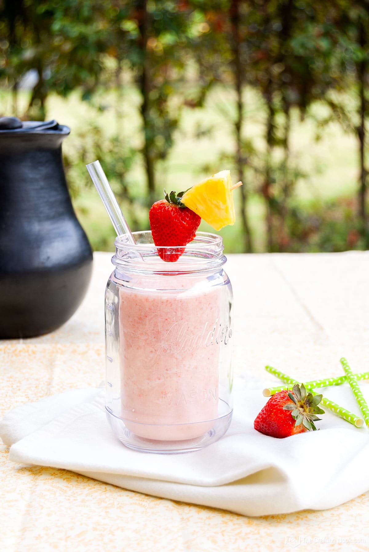 front view of glass with Strawberry Pina Colada on a table decorated with strawberries and straws