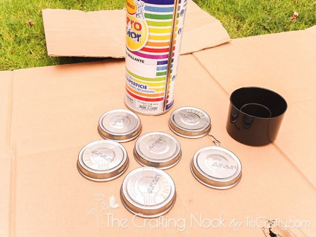 view of jar lids and a spray paint can on cardboard