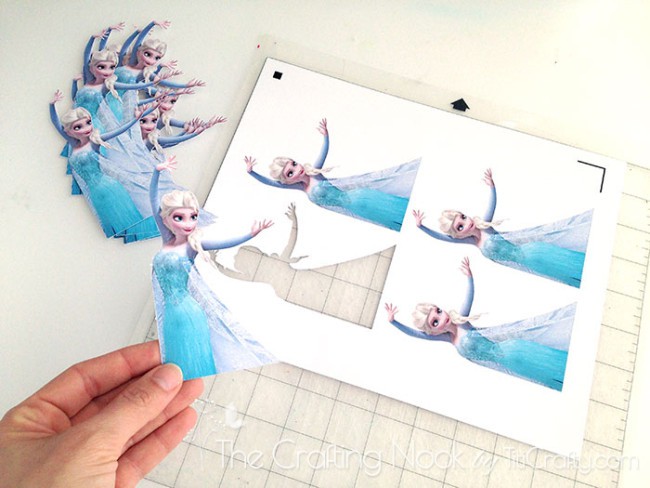 top view of hand holding figure of Elsa cutout printed on paper
