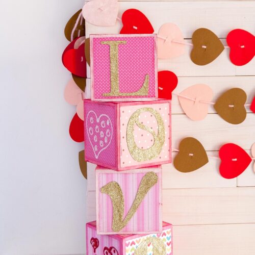 DIY Love Wood Letter Blocks for Valentine’s Day in different pink shades and gold letters. Feature image