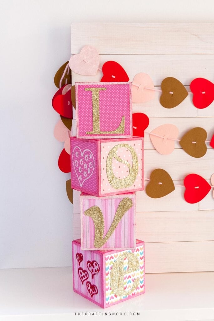 DIY Love Wood Letter Blocks for Valentine’s Day in different pink shades and gold letters. Feature image