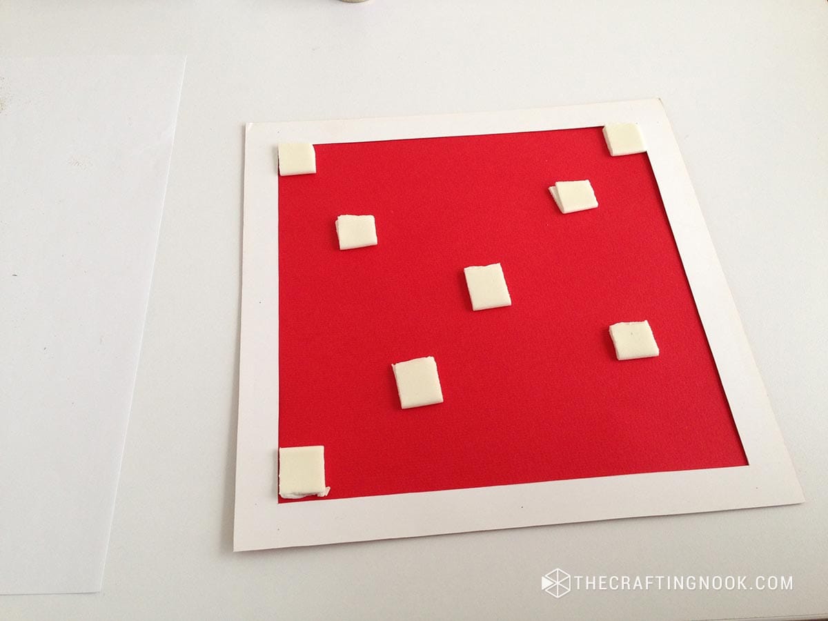 double-sided tape applied to the corners of the back of the red cardboard