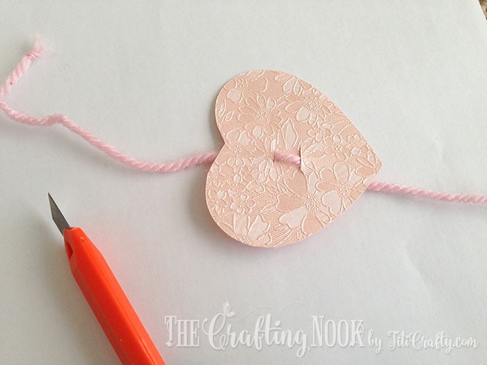 The pink heart with the yarn string inserted through the cuts