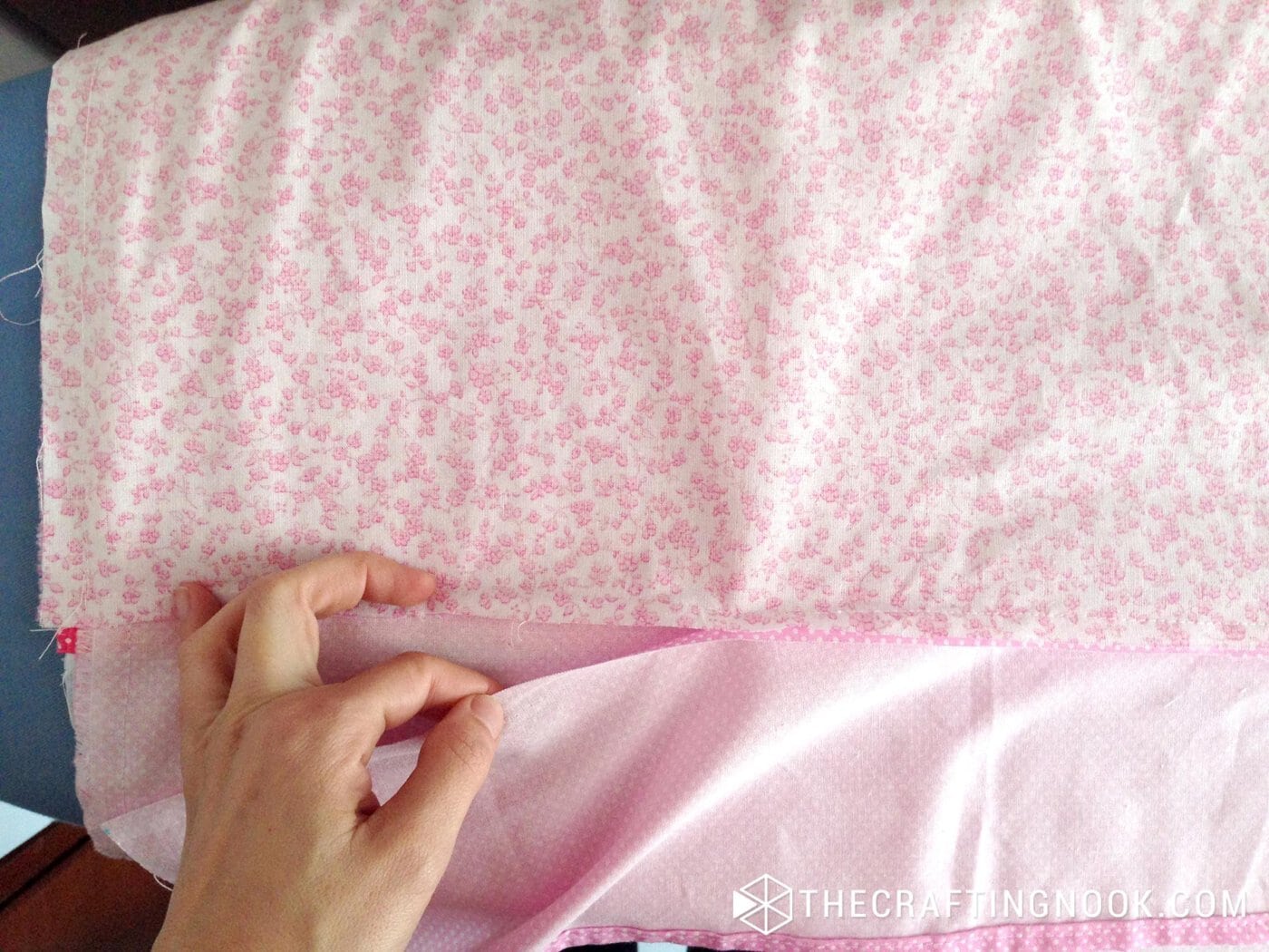 showing the hand folding the edge of the fabric that is going to be sewn inside the duvet
