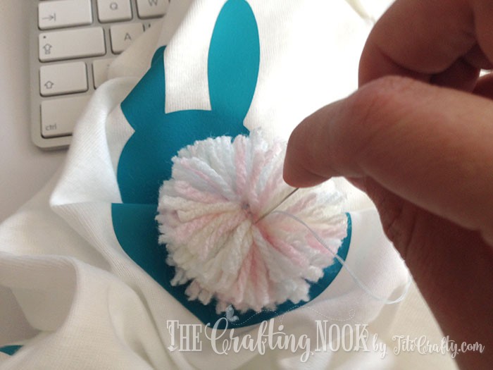 view final stitching the pompom to the onesie