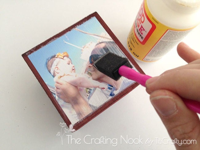 applying the mod podge on the photos and the wooden cube