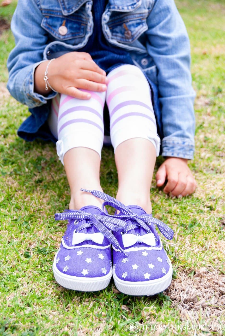 View of legs of girl with star rhinestone shoes sitting on grass