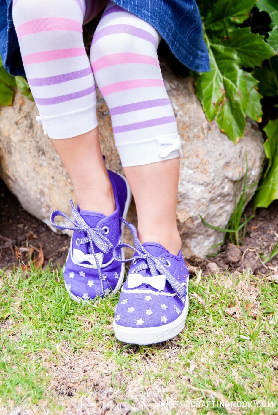 A girl sitting on a big rock wearing the DIY Rhinestone Shoes