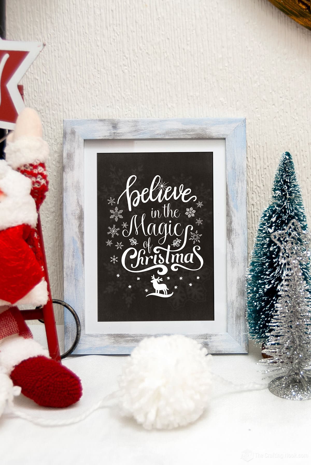 FREE Christmas Chalkboard Art Printable Version 1 in a photo frame on a christmas decorated table