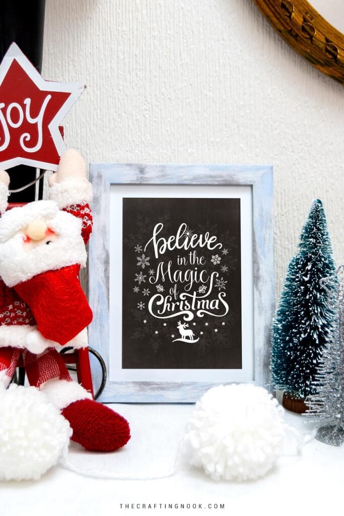 FREE Christmas Chalkboard Art Printables in a photo frame on a christmas decorated table Cover Image