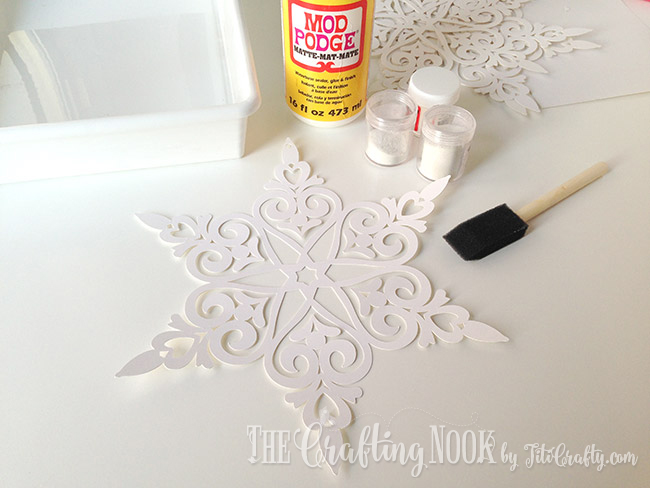 view of snowflake on paper and supplies for glitter