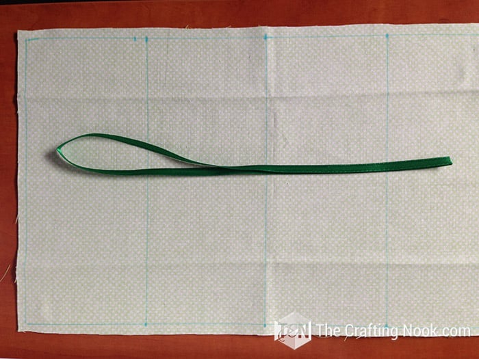 view of string of ribbon on open fabric marked with measurements
