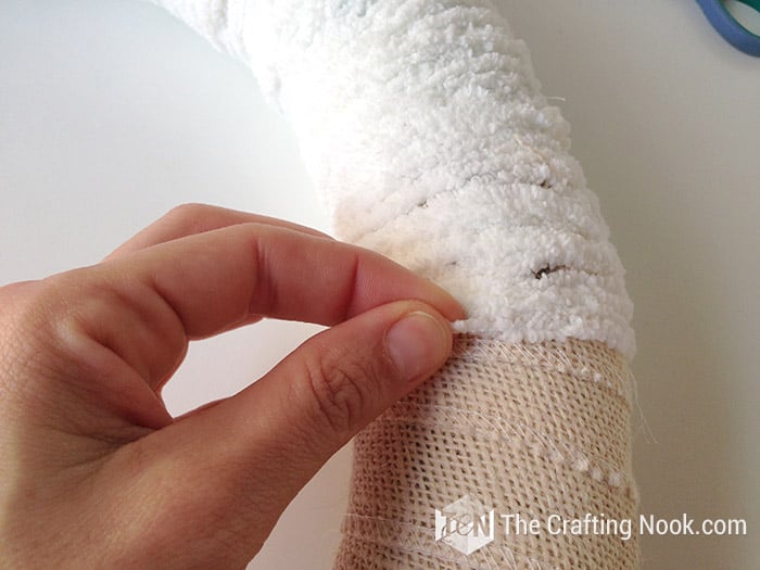 tying a knot to secure the white yarn on the back of the wreath