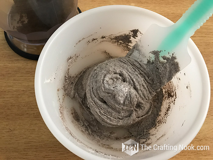 top view of crushed Oreos and frosting in a bowl already mixed with a pastry palette
