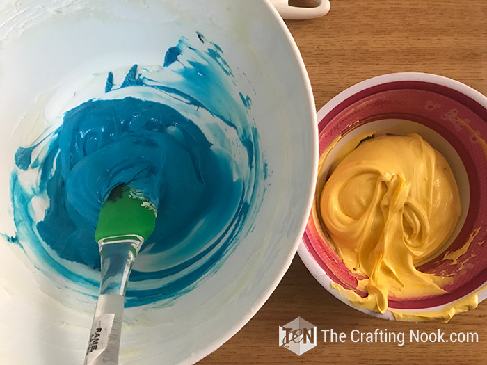 top view of frosting inside a bowl of blue and yellow colors
