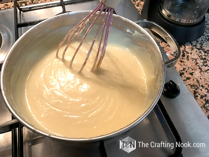 close up view of condensed milk in the pot along with a hand whisk