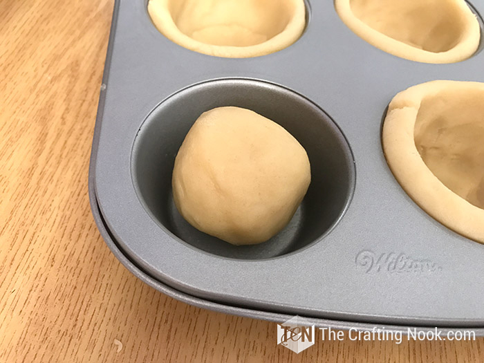 close up image of ball of dough on cupcake tray