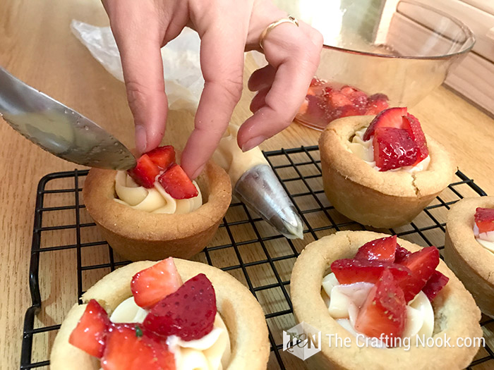 image of my hand placing the strawberries on the cookie cup
