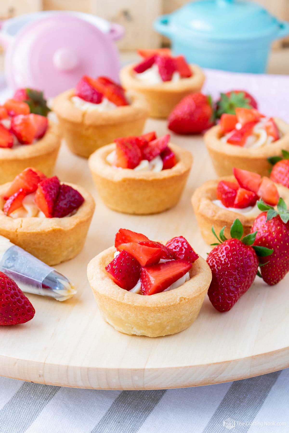 45 degree angle shot of a bunch of Strawberries and Cream Cookie Cups on a dray decorated with whole strawberries and a piping bag