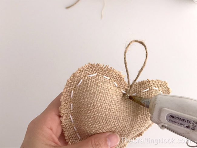 applying hot glue a hanger twine with the shape (heart)