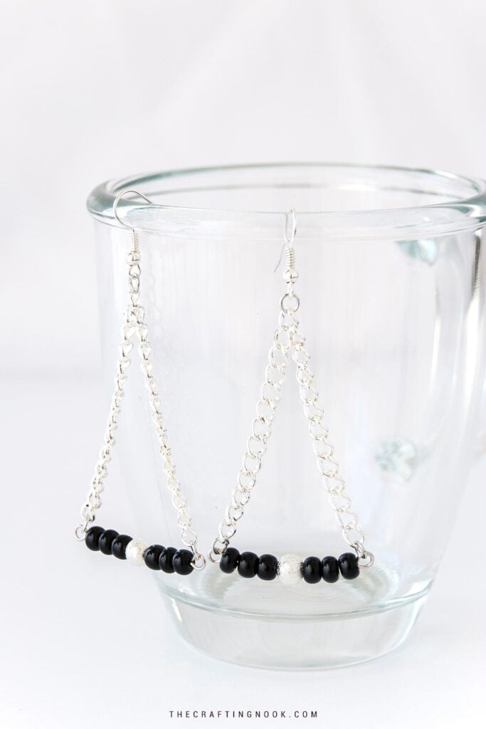 Silver triangle dangle earrings with black beads and chain details.