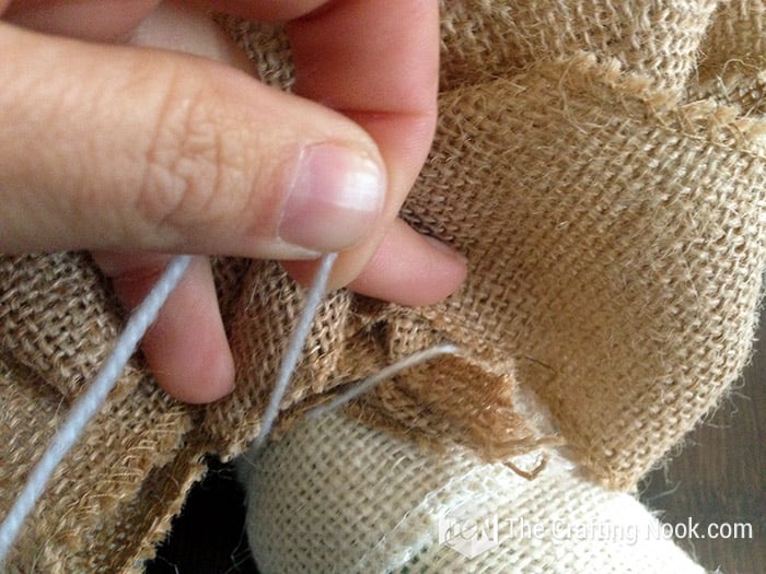 close up image securing the burlap with the thread