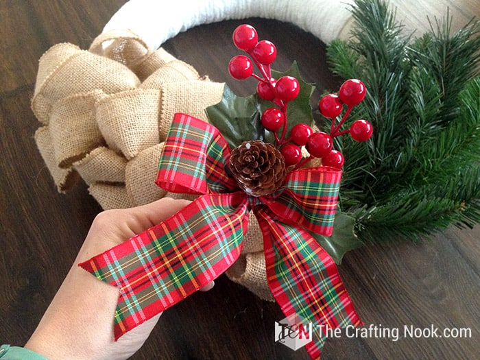 showing  a bow with a plaid ribbon with red berries