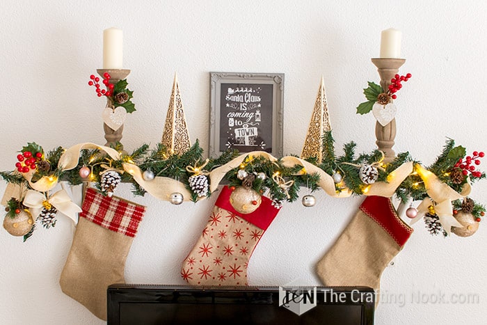 general view of mantel decorated with light burlap ribbon, battery-powered lights, some of my flocked pinecones, Christmas ornaments, cranberry springs, and other rustic ornaments