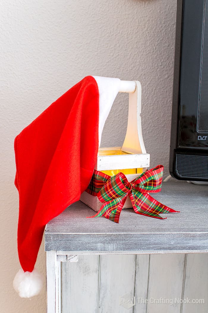 closeup of wooden candle holder on  with a plaid bow and a Santa hat