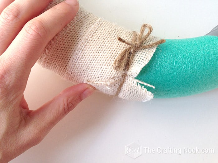 Securing the ends of the burlap ribbon with twine