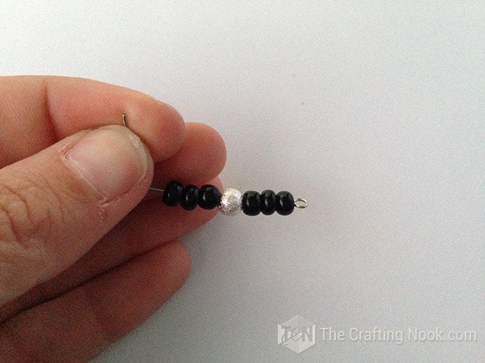 view of eye pin with 3 black beads, 1 solver bead and 3 black beads